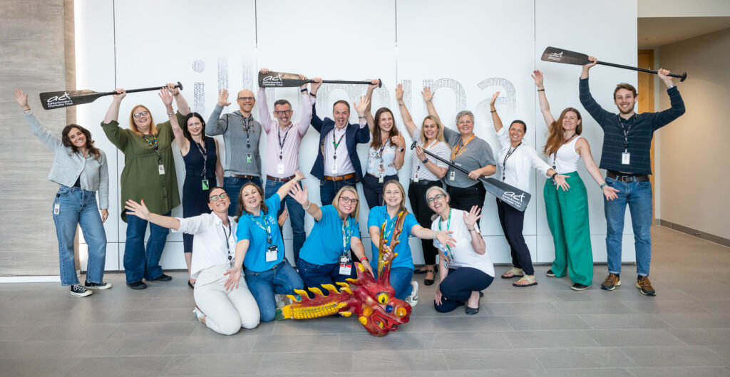 Illumina and ACT teams holding up oars and posing with Dragon boat head