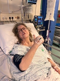 Patient Stephanie Hemming lying in bed as a patient doing a thumbs up